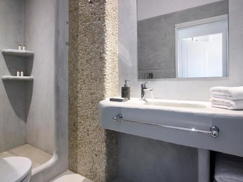 a bathroom with a sink and a toilet and a mirror at Delmar Apartments & Suites Milos - Delmar Collection in Pollonia