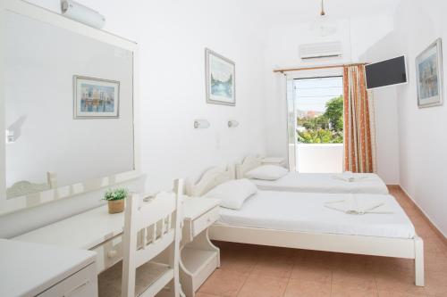 2 Betten in einem weißen Zimmer mit Fenster in der Unterkunft Louiza Hotel in Parikia