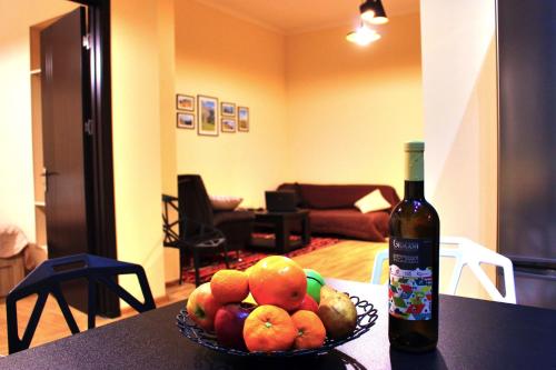 una ciotola di frutta su un tavolo accanto a una bottiglia di vino di Yango Apartment a Tbilisi City