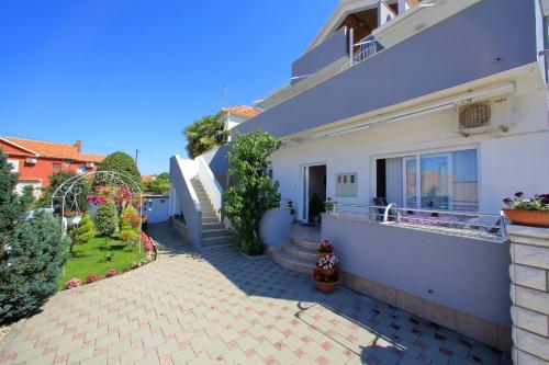a white house with a patio and a yard at Apartment Šime Bibinje in Bibinje