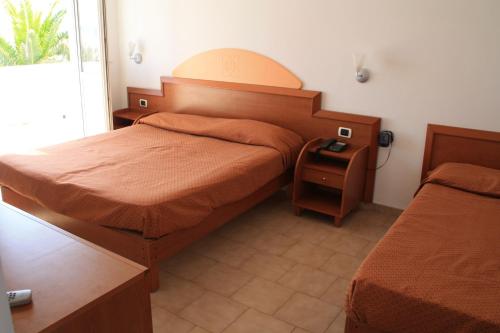a bedroom with two beds and a table and a window at Hotel Villaggio Club Altalia in Brancaleone Marina