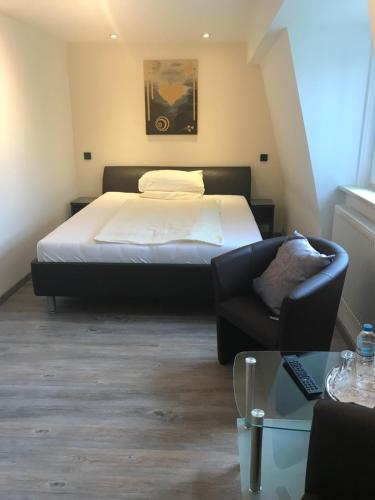 a bedroom with a bed and a chair and a couch at Hotel Friedrich in Hachenburg