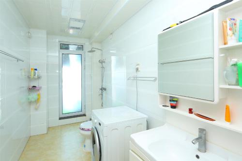 La salle de bains blanche est pourvue de toilettes et d'un lavabo. dans l'établissement 青岛金沙滩全家幸福三居室海景公寓Blessed Family Apartment, à Qingdao