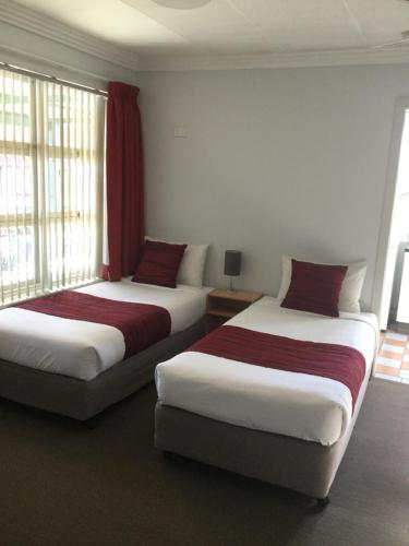two beds sitting in a room with windows at Bargo Motor Inn in Bargo