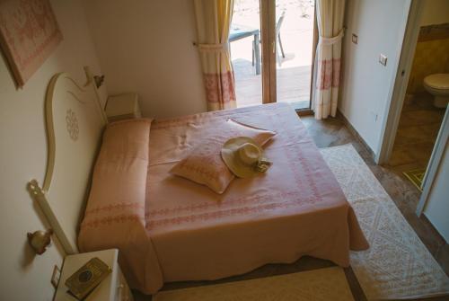a bedroom with a pink bed with a hat on it at Hotel Barbagia in Dorgali
