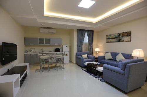 a living room with two blue couches and a kitchen at Arjaan Altakhassusi Hotel Suites in Riyadh