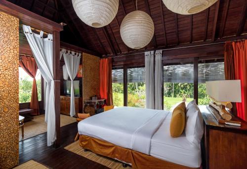 a bedroom with a bed in a room with windows at Villa Padi Menari in Ubud
