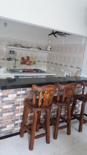 a kitchen with wooden chairs and a counter with a sink at Casa Campestre La Heredera in Villavicencio