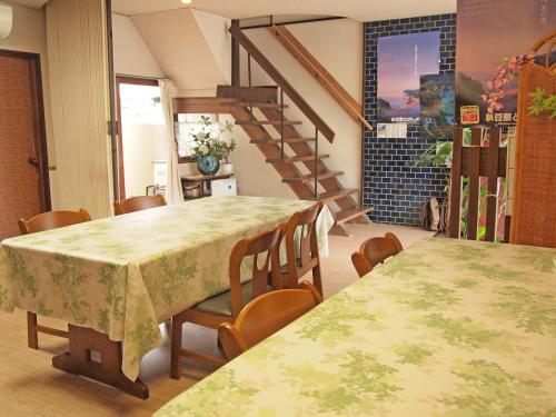 uma sala de jantar com duas mesas e uma escada em Kikuya Ryokan em Tonosho