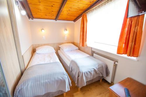 two beds in a small room with a window at Pokoje Gościnne Justynka in Władysławowo