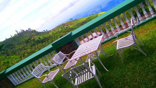 four white chairs sitting next to a fence with a mural at Srilak View Holiday Inn in Haputale