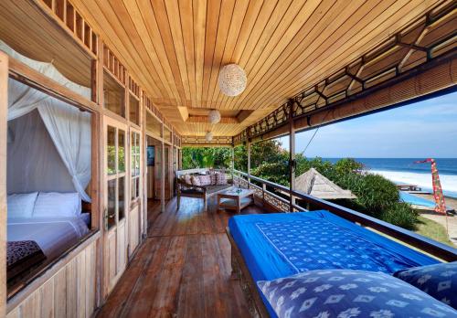a porch with a bed and a view of the ocean at Jasri Bay Hideaway in Jasri