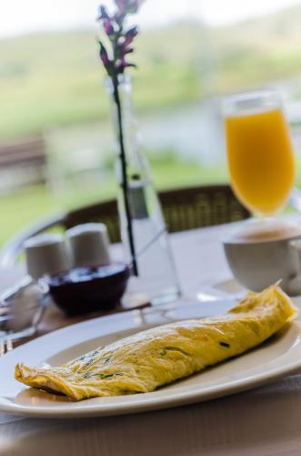 un pezzo di cibo su un piatto con un bicchiere di succo d'arancia di Gowrie Farm Golf Lodge a Nottingham Road