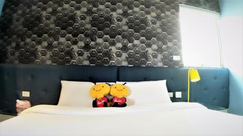 twee knuffeldieren zitten op een bed bij Honey B Trip B&B in Hualien
