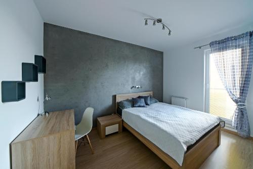 a bedroom with a bed and a desk and a window at Apartamenty City View od WroclawApartament-pl in Wrocław