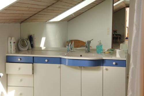 a white kitchen with a sink and a mirror at Skovlide Beautiful Farmhouse in Edslev