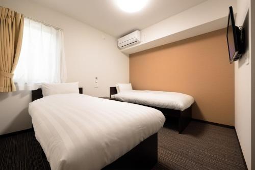 um quarto de hotel com duas camas e uma janela em La'gent Inn Kesennuma em Kesennuma