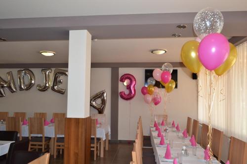 a row of tables with pink and gold balloons at Tihe Noci Motel in Pale