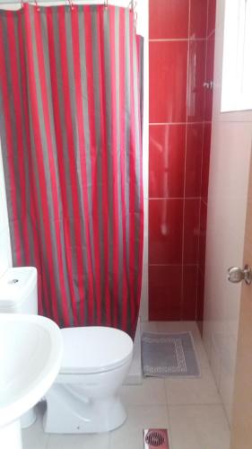 a bathroom with a red shower curtain and a toilet at Paritsa Hotel in Kos Town