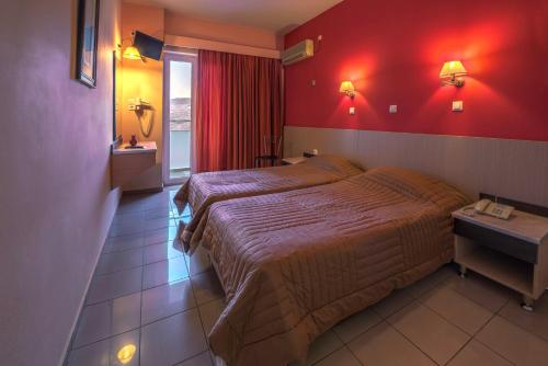 a bedroom with a large bed and a red wall at Paritsa Hotel in Kos Town