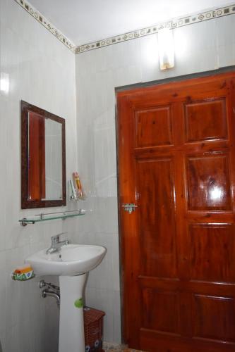 a bathroom with a wooden door and a sink at Van Long Family Homestay in Ninh Binh