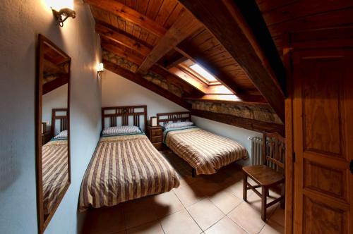 two beds in a room with a wooden ceiling at El Invernal de Picos in Portilla de la Reina