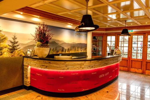 a bar in a restaurant with a large painting on the wall at Hotel Heselbacher Hof in Baiersbronn