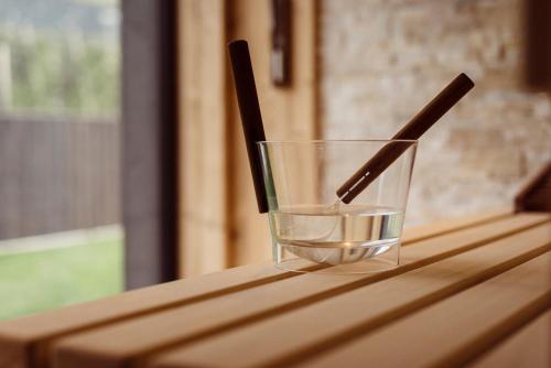 two chopsticks in a glass on a wooden table at Hotel Restaurant Kirchsteiger in Vollan