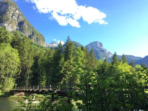 a bridge over a river with mountains in the background at Landhaus Lilly in Obertraun