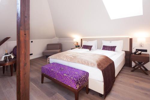 a bedroom with a large white bed and a purple stool at Boutique Hotel Adria in Wels