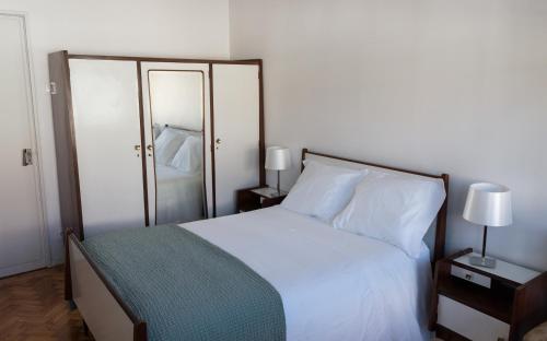 a bedroom with a white bed and two lamps and a mirror at Family Espinho Porto Guesthouse in Espinho