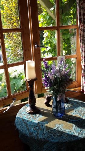 a table with a candle and a vase of purple flowers at Romantisch Huisje nabij het strand met uitzicht op de tulpenvelden in Julianadorp