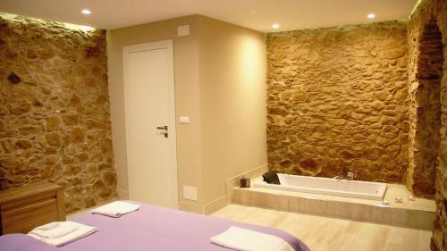 ein Badezimmer mit einer Steinmauer und einer Badewanne in der Unterkunft Kaaba - Aragon home holiday in Montalbano Elicona