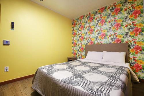 a bedroom with a bed with a floral wall at Su Motel in Buyeo