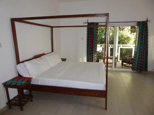 1 dormitorio con cama con dosel y patio en Sarawally Guesthouse, en Ampaya