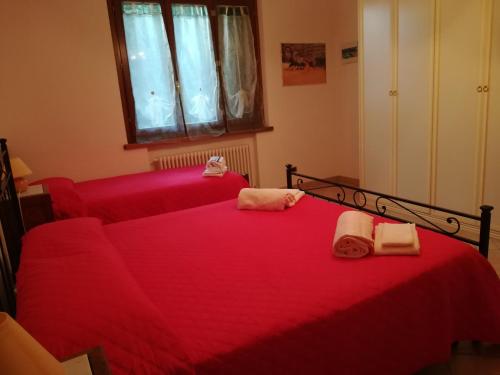 a bedroom with two beds with red sheets and towels at Il Giardino degli Ulivi in Rapolano Terme