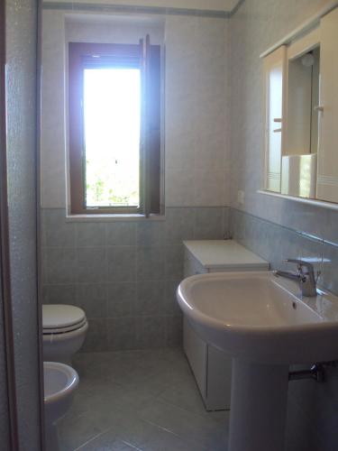 a bathroom with a sink and a toilet and a window at Residenza Piccolo Uliveto in San Menaio