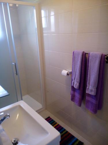 a bathroom with a sink and a shower with purple towels at Rooms Marina in Korenica