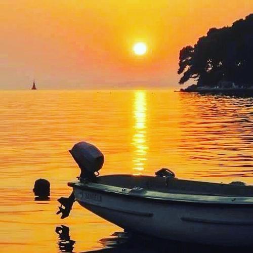 a boat sitting in the water at sunset at Hostel Marina Trogir in Trogir