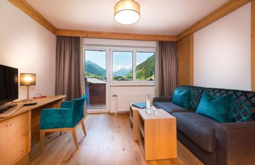 sala de estar con sofá, mesa y ventana en Hotel Alpina en Rauris