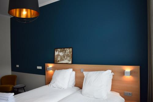 a bedroom with a blue wall and a bed with white pillows at Hotel In't Holt 1654 Grand Café & Logement in Zuidhorn