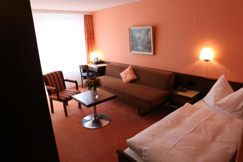a hotel room with a couch and a chair at Hotel-Restaurant Seegarten-Marina in Spiez