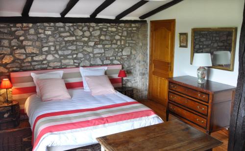 a bedroom with a bed and a stone wall at Chambres d'hôtes Gela Itsasoa Océan in Ciboure