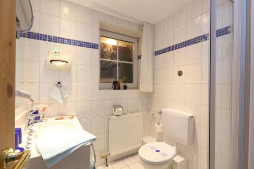 a white bathroom with a toilet and a sink at Landhotel Grimmeblick in Winterberg