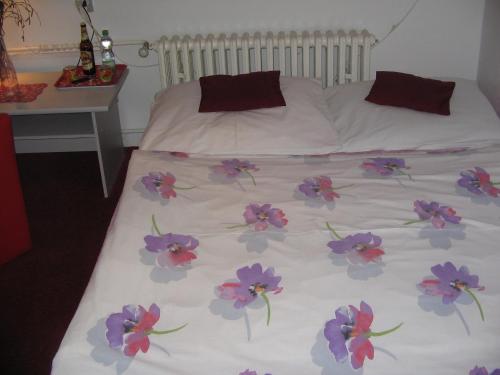 a white bed with purple flowers on it at Penzion Zavodsky in Český Krumlov