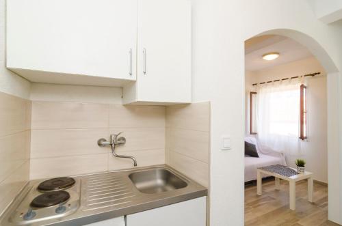 a kitchen with white cabinets and a sink in a room at Apartments Vitorin in Sobra