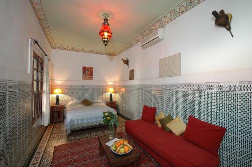 a living room with a red couch and a bed at Riad El Sagaya in Marrakech