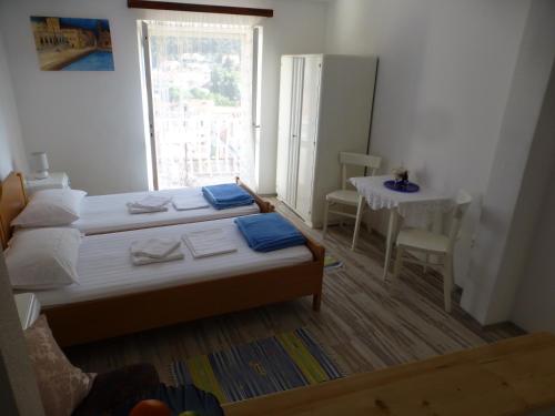 a bedroom with two beds and a table and a window at Guesthouse Bracanović in Hvar