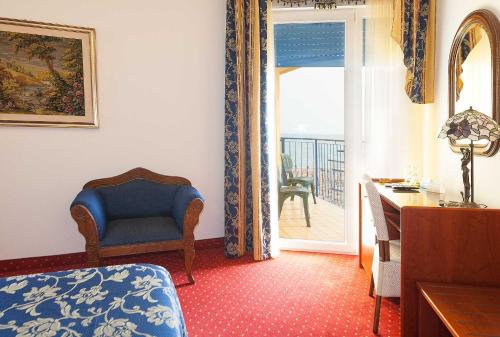 a living room with a blue chair and a door to a balcony at Hotel Napoleon in Lido di Jesolo