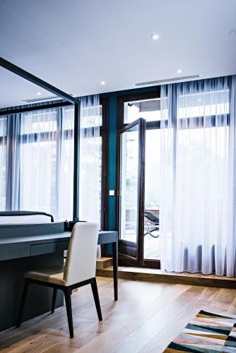 a desk and a chair in a room with windows at Auberge Du Père Bise - Jean Sulpice in Talloires